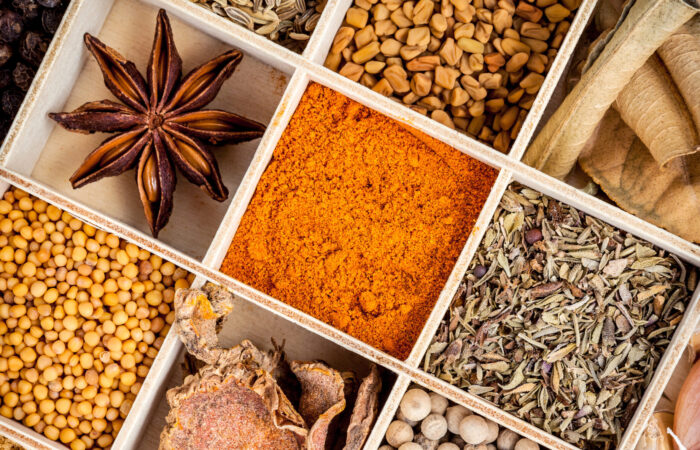 Assortment of spices ingredients in wooden box on wooden table.